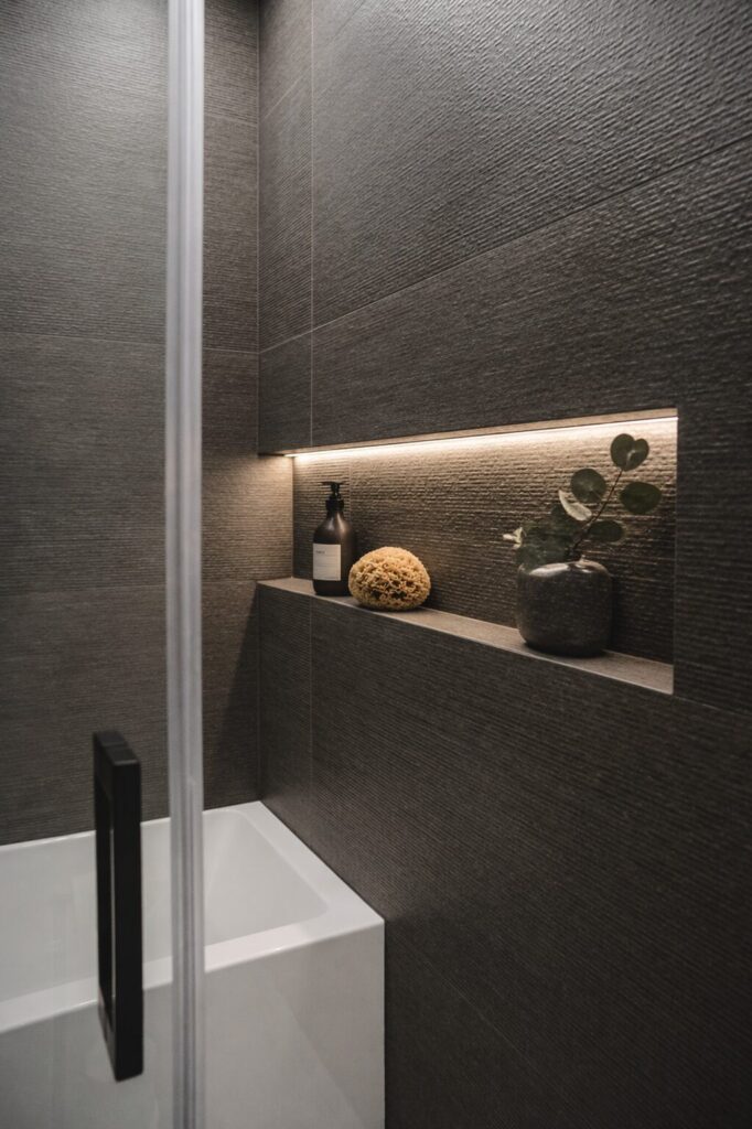 Détail d’une niche de douche éclairée avec tablette intégrée, finition céramique haut de gamme et ambiance spa, projet de salle de bain à Saint-Bruno-de-Montarville
