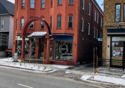 Immeuble patrimonial commercial avant rénovation sur la rue Principale à Granby, avec façade en brique rouge, fenêtres architecturales d’origine et entrée centrale voûtée.